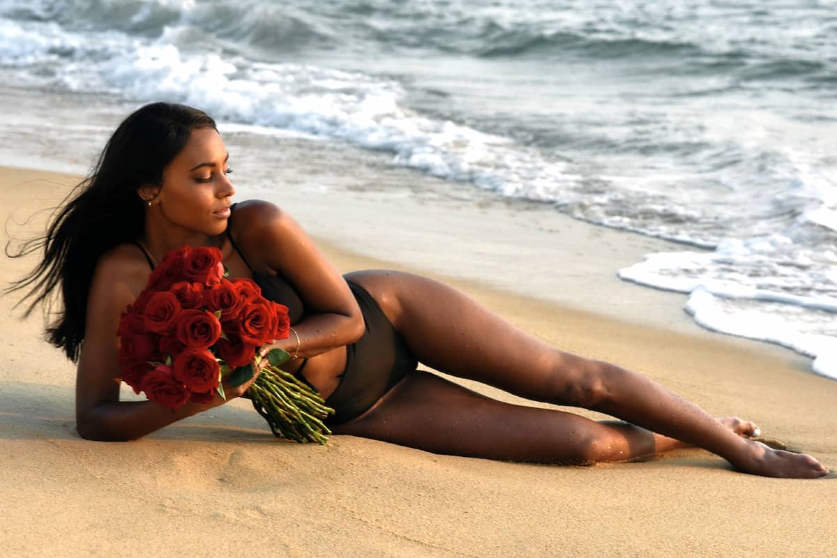 Sharon Battiste als Bachelorette 2022 - hier im Bild liegt Sharon am Strand mit einem Strauß Rosen in der Hand
