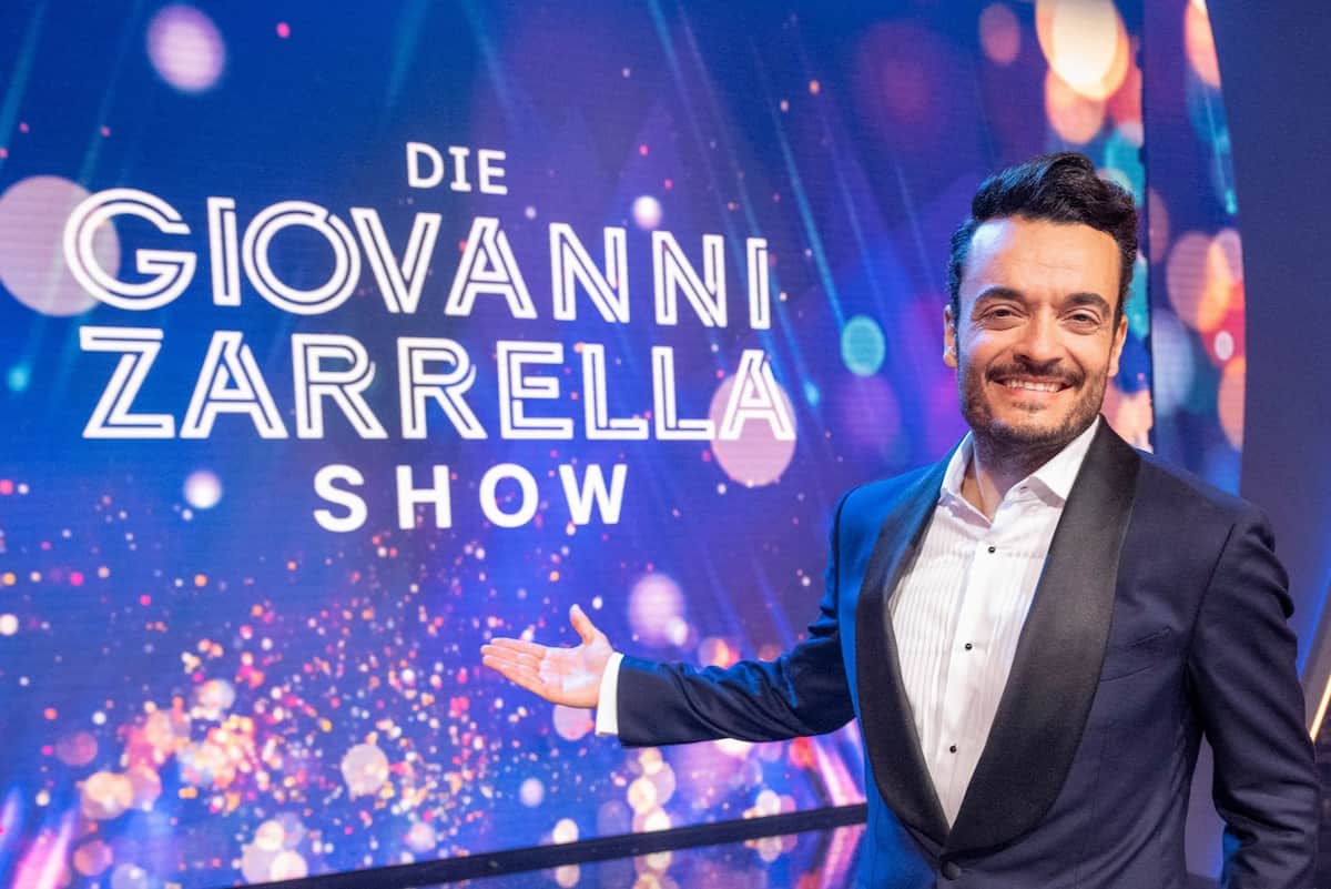 Giovanni Zarrella Show 22.7.2023 im ZDF TV-Kritik, Alle Gäste in Dortmund - hier im Bild der Gastgeber Giovanni Zarrella auf der Show-Bühne vor dem Logo der Show im Hintergrund