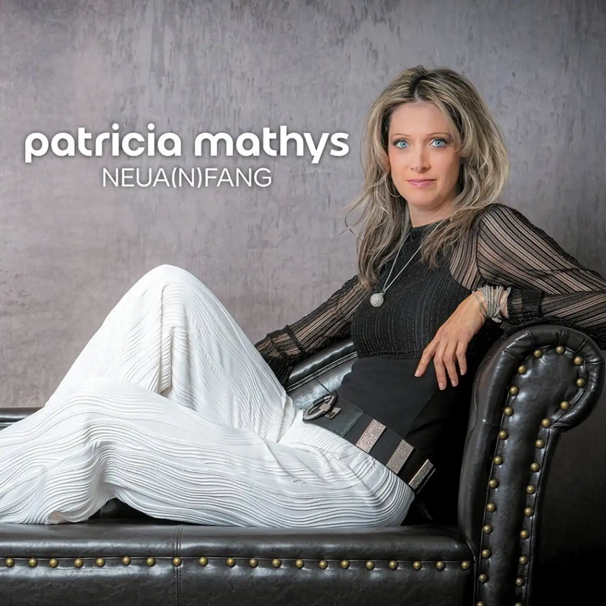 Patricia Mathys Album “Neua(n)fang” 2025 - im Bild das Album-Cover mit der Sängerin, die auf einem Longchair (Ottomane) sitzt