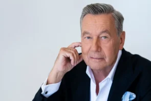 Roland Kaiser kündigt ein neues Live-Album an - Sänger in dunkelblauen Anzug schaut mit nachdenklicher Geste in die Kamera