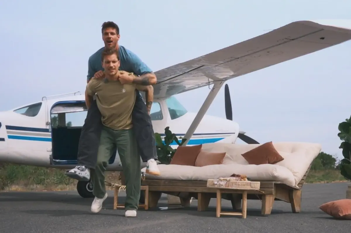 Bachelors Felix und Martin in Folge 7 am 6.8.2025 nach ihren Einzel-Dates vor einem Flugzeug - Felix nimmt Martin huckepack, weil der sich sich am Fuß verltzt hat