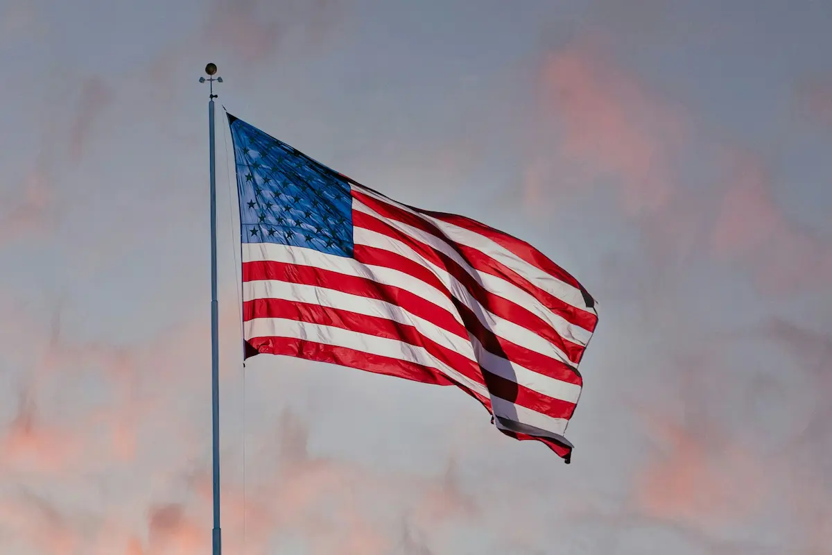 Eiskunstlauf, Isabeau Levito Erster Erfolg der Saison beim Cranberry Cup 2025 in den USA - auf dem Foto zur Illustration ist eine amerikanische Flagge zu sehen, die bei Sonnenaufgang im Wind weht