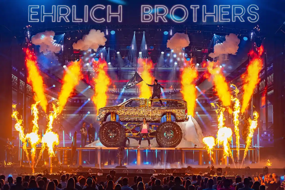 Andreas Ehrlich und Chris Ehrlich mit einem Monster-Truck auf der Bühne ihrer Show