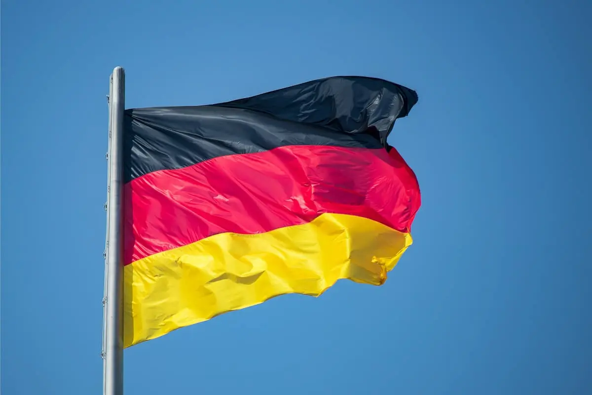 Eiskunstlauf Deutsche Meisterschaft 2026 Ergebnisse am 12.–13. Dezember 2025, Zeitplan in Oberstdorf, Live-Streams (Übertragungen) - auf dem Foto zu sehen ist eine Deutsche Flagge, die vor blauem Himmel im Wind flattert