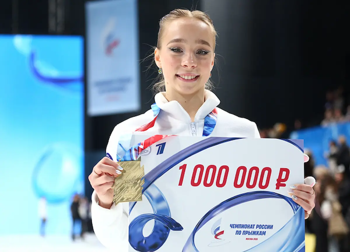 Alisa Dvoeglazova - Gewinnerin der Russischen Sprung-Meisterschaft 2026 bei der Siegerehrung - die Eiskunstläuferin lächelt in die Kamera und zeigt ihre Goldmedaille und ihren Siegerscheck