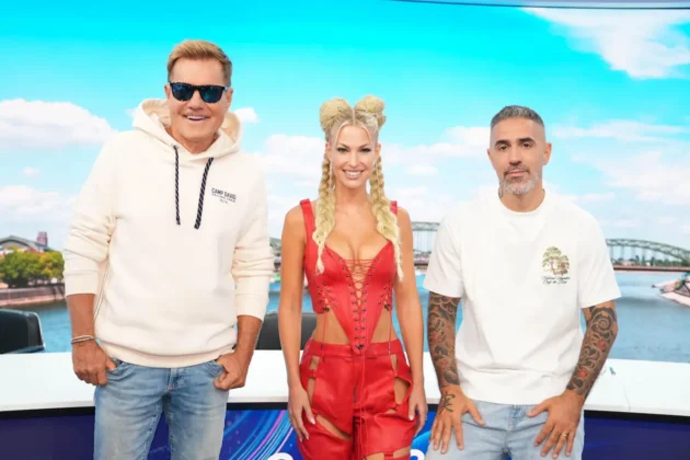 DSDS 2026 - Übersicht über die neue Staffel der Casting-Show - hier im Bild die Jury-Mitglieder Dieter Bohlen, Isi Glück und Bushido, die während der Jury-Castings vor dem Jury-Pult und einem Kulissenbild von Köln (dort waren die Jury-Castings) stehen. Dieter Bohlen trägt Jeans und einen weißen Hoodie, Isi Glück trägt eine gewagte Kombination aus roten Leder - eine Hose mit Outcuts und ein geschnürtes Bustier, Bushido trägt ein schlichstes, weißes T-Shirt und Jeans