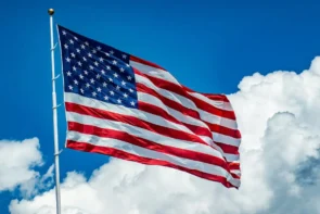 Eiskunstlauf-Meisterschaft USA 2026 Ergebnisse, Zeitplan 5.–10. Januar 2026 - das Foto zeigt die US-amerikanische Flagge, die vor einem blauen Himmel mit einzelnen Wolken im Wind flattert