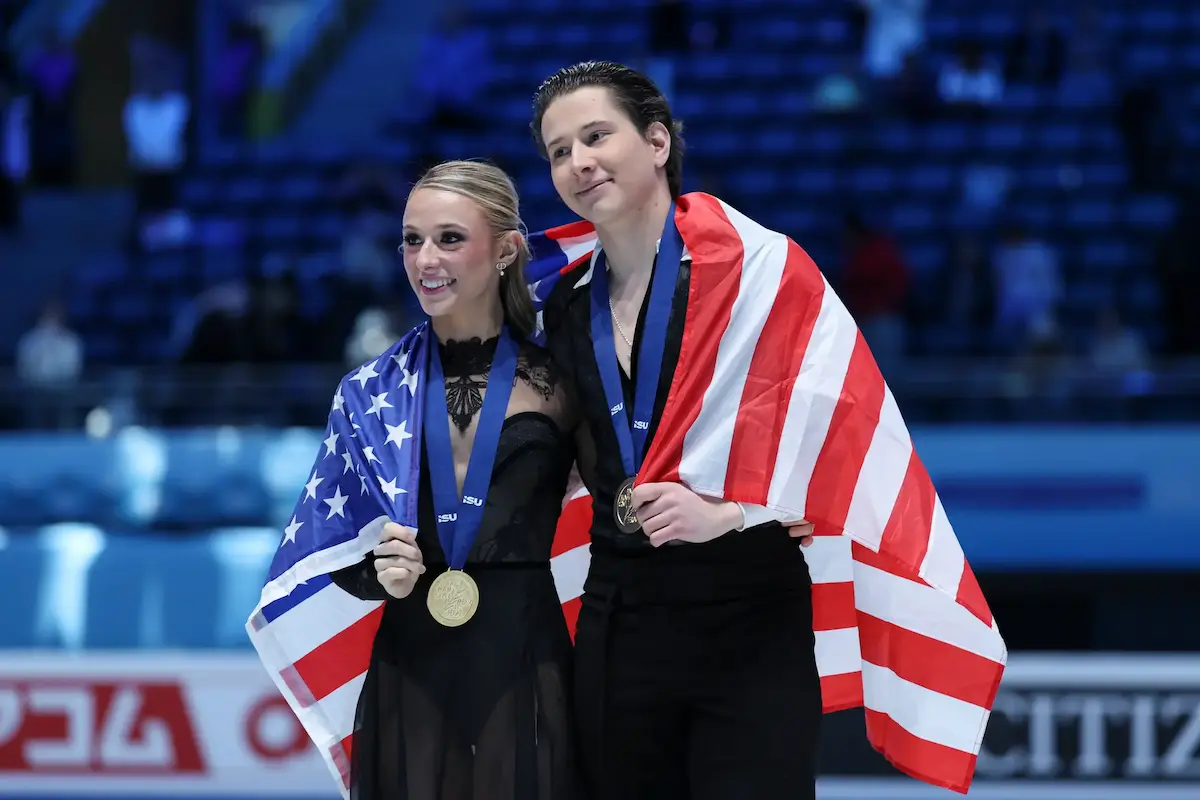 Emilea Zingas - Vadym Kolesnik aus den USA - 4CC-Meister 2026 bei den Eistanz-Paaren - das Bild zeigt das Eistanz-Paar nach der Siegerehrung, sie zeigen lächelnd ihre Goldmedaille und haben sich eine US-Flagge um die Schultern gehängt