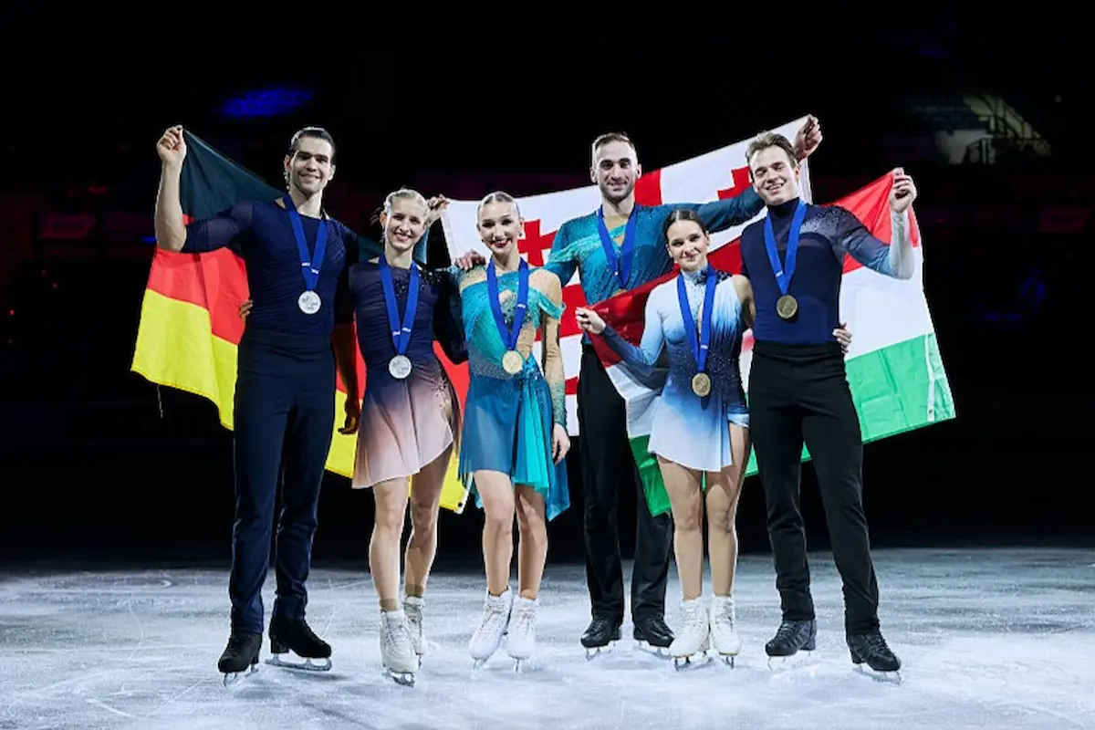Ergebnis Eiskunstlauf-Paare bei der Eiskunstlauf-EM 2026 - Siegeehrung - hier im Bild die drei Medaillen-Paare Metelkina & Berulova, Hase & Volodin und Pavlova & Sviatchenko. die jeweils ihre Landesflaggen hinter sich ausbreiten