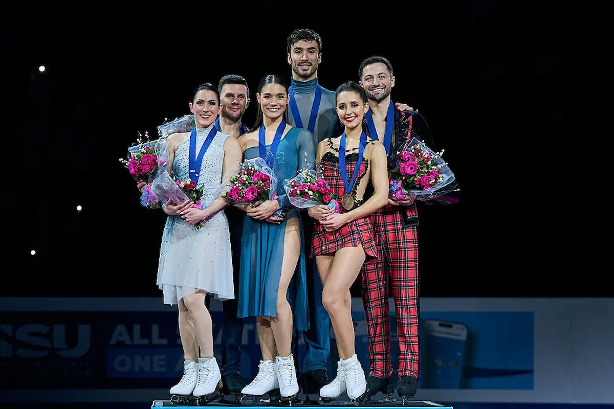 Ergebnis Eistanz-Paare bei der Eiskunstlauf-EM 2026 - Siegerehrung - hier im Bild die drei Eistanz-Paare, die Medaillen Gold Silber und Bronze gewonnen haben - es ist das Sieger-Foto, die Sportler haben die Medaillen umgehängt und halten Blumensträuße in den Händen