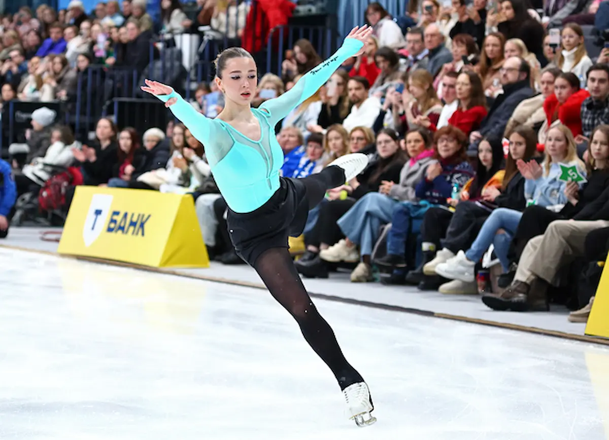 Kamila Valieva bei der Russischen Sprung-Meisterschaft 2026 - der erste Wettbewerb der Eiskunstläuferin nach ihrer Dopingsperre. Das Bild zeigt Kamila Valieva nach einem Sprung. Sie träg ein einfaches Eislauf-Dress mit einem türkisfarbenen Oberteil, schwarzen Leggins und einem kurzen Tüllrock darüber.