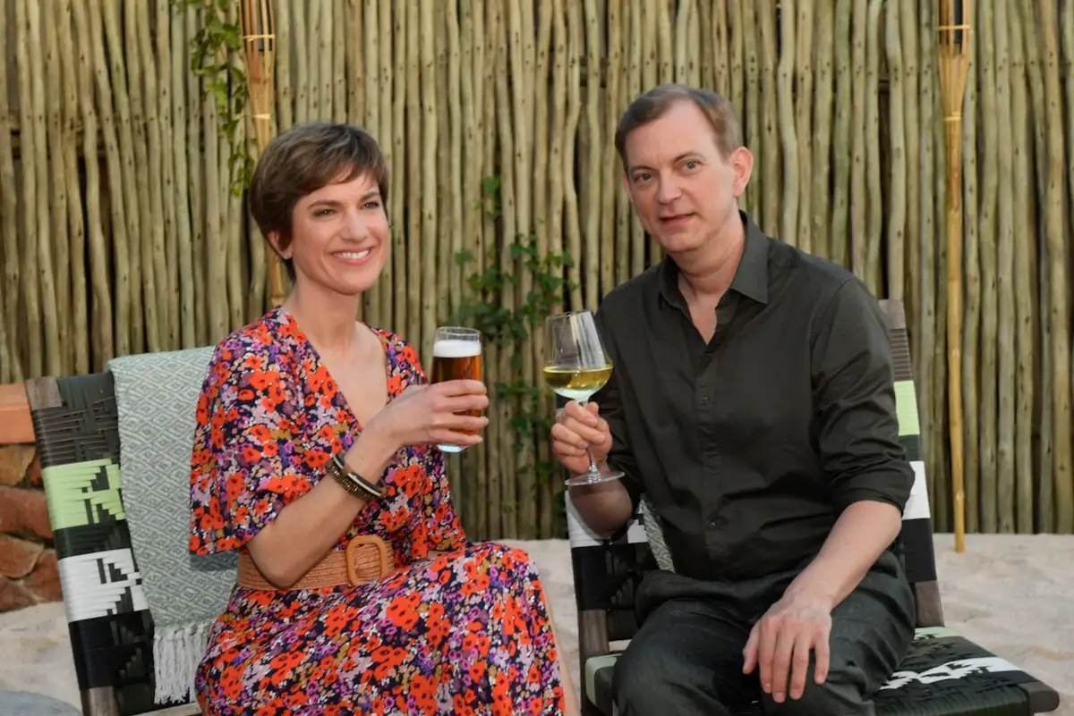 Katja Sommer (Isabell Horn) und Björn Wagner (Daniel Krauss) beim Traumschiff 1. Januar 2026 - das Paar sitzt nebeneinander, beide halten ein Getränk in der Hand und lächeln in die Kamera