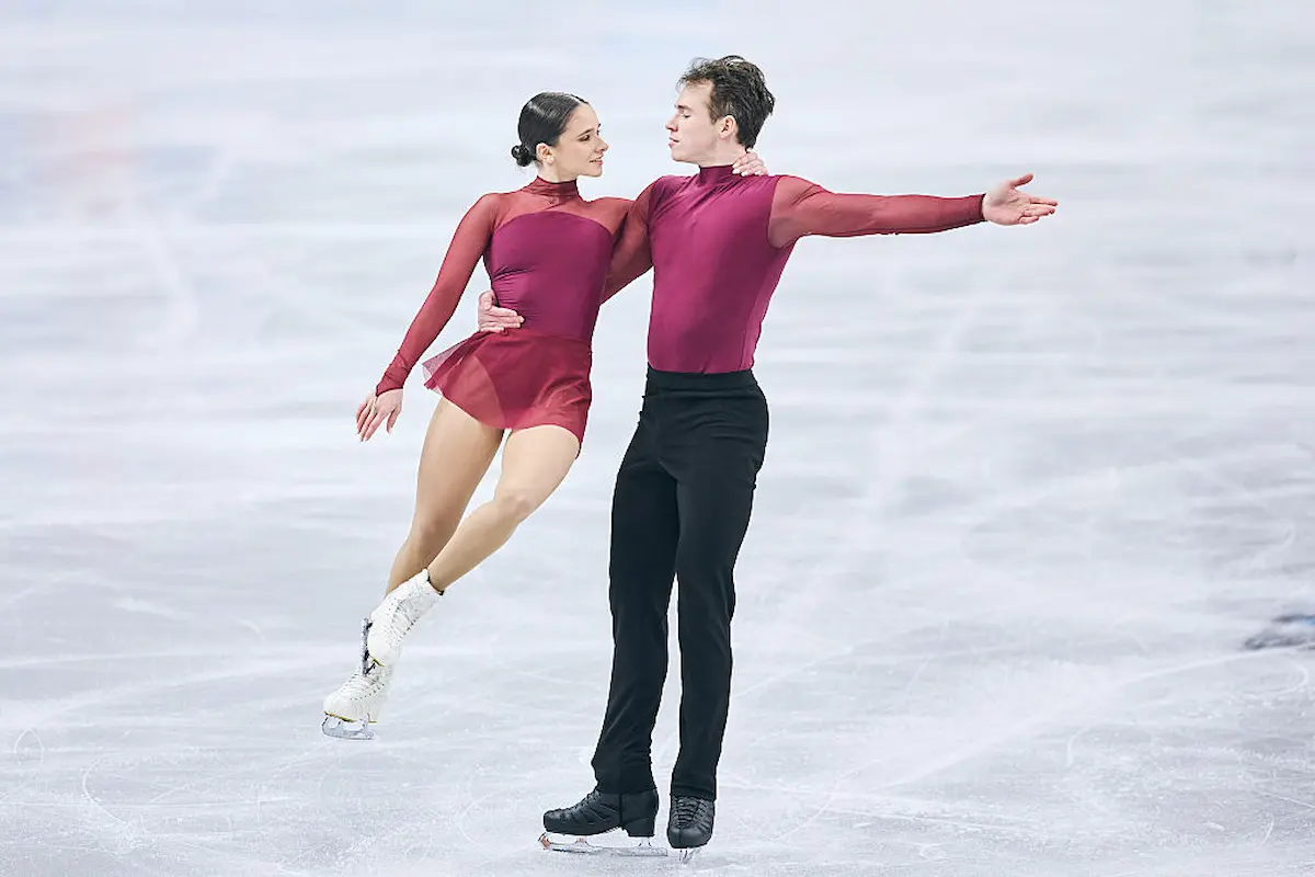 Maria Pavlova - Alexei Sviatchenko aus Ungarn bei der Eiskunstlauf-EM 2026 in Sheffield im Kurzprogramm - das Foto zeigt das Eiskunstlauf-Paar auf dem Eis, beide tragen ein weinrotes, sehr schlichtes Outfit, optisch ähnlich, wie es Balletttänzer im Training tragen könnten
