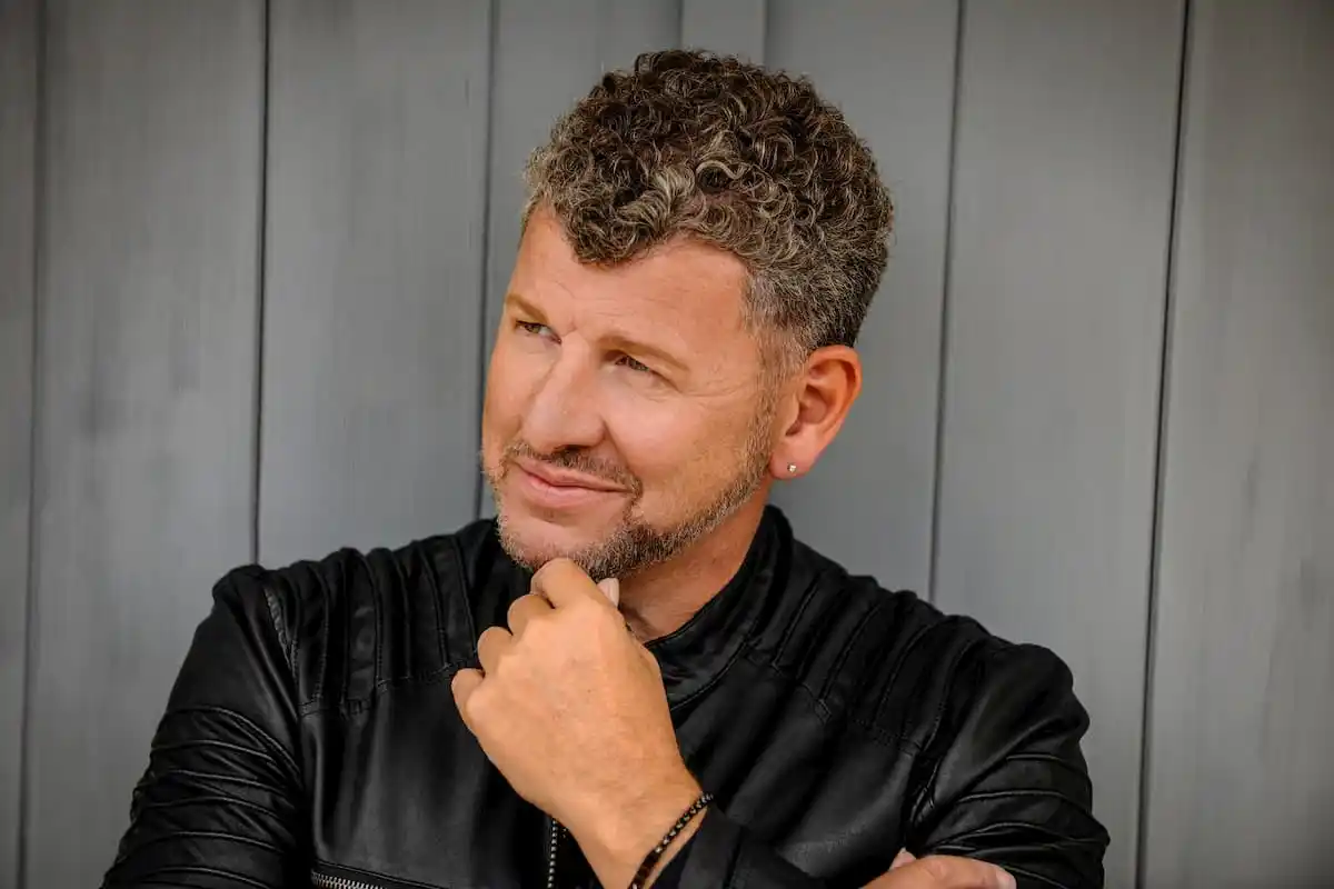 Semino Rossi 2026 Konzert-Termine, Städte, Orte und Ticket-Tipps - hier im Bild eine Portrait-Aufnahme des Künstlers in einer schwarzen Lederjacke, er hält die Hand am Kinn und schaut lächelnd auf etwas neben der Kamera