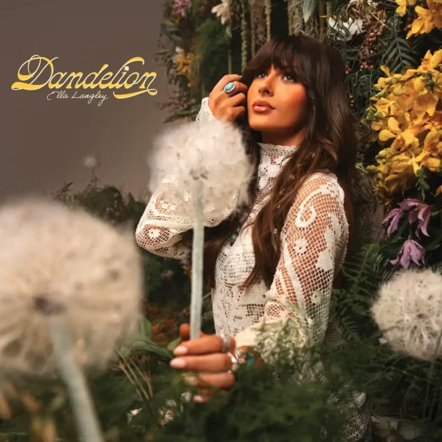 Country 2026: Ella Langley - Neuer Song veröffentlicht und Album „Dandelion“ angekündigt - Das Bild zeigt das Album-Cover mit einem Foto der Künstlerin - sie trägt ein weißes Spitzenkleid, sitzt in einem Blumen-Arrangement und hält eine Pusteblume in der Hand