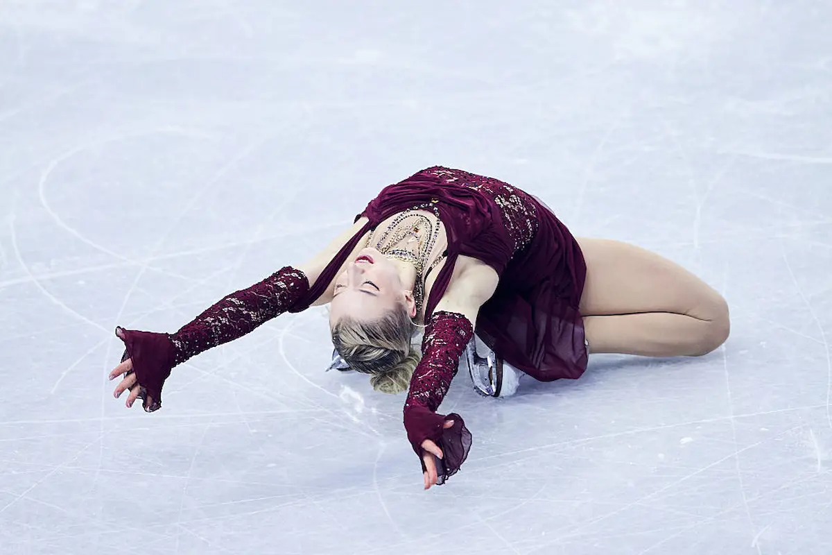 Amber Glenn bei der Eiskunstlauf-Weltmeisterschaft 2026 im Kurzprogramm - das Foto zeigt die Eiskunstläuferin in der Schlusspose des Kurzprogramms - sie trägt ein weinrotes Kostüm mit viel Spitze