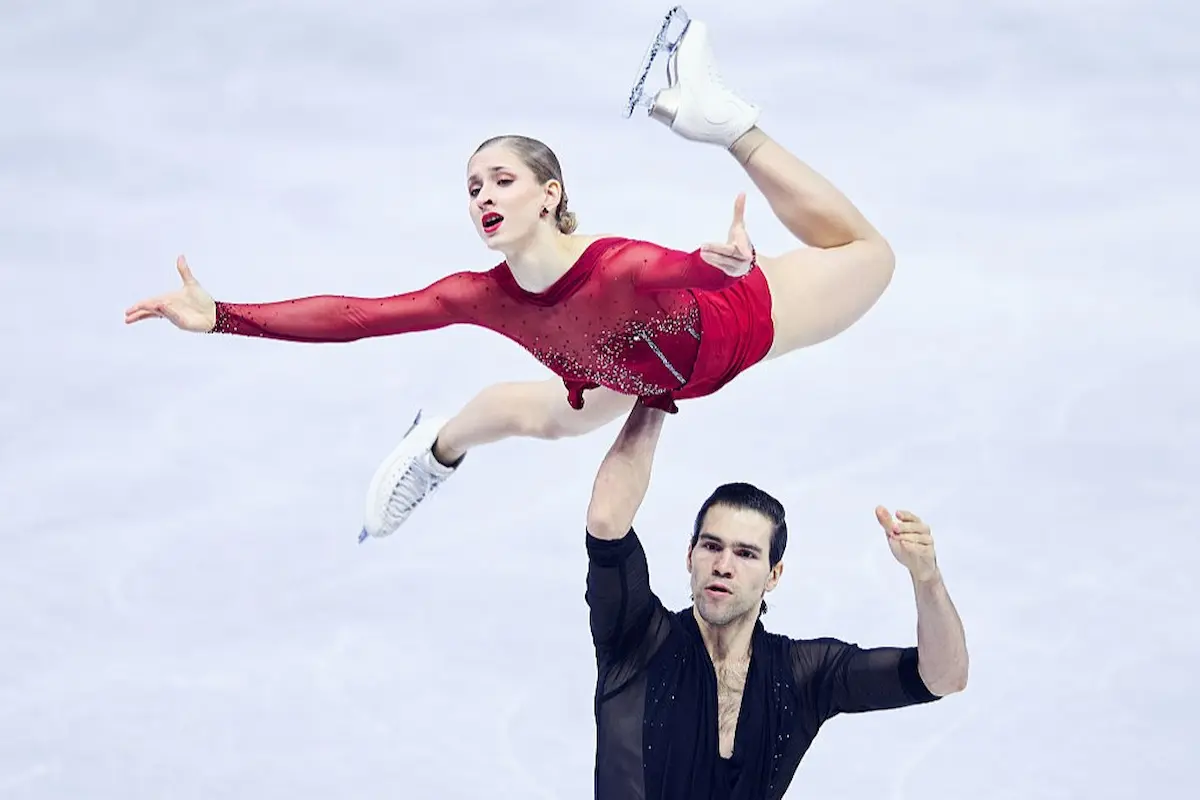 Minerva Fabienne Hase und Nikita Volodin bei der Eiskunstlauf-WM 2026 in Prag im Kurzprogramm - das Foto zeigt Minerva Fabienne Hase bei einer Hebung in ihrem neuen, weinroten Kleid in einem angenehmen Kontrast zum schwarzen Kostüm von Nikita Volodin