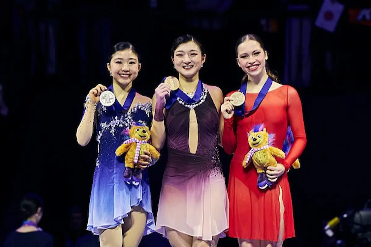 Siegerehrung Frauen Eiskunstlauf-WM 2026 - im Bild zu sehen Mone Chiba, Kaori Sakamoto und Nina Pinzarrone, die ihre Medaillen in die Kamera halten und lächeln