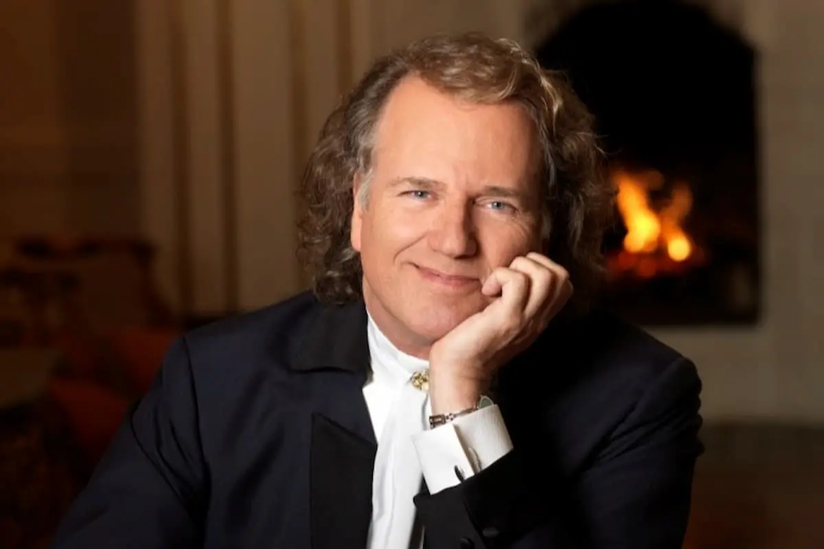 Andre Rieu Konzerte 2027 - Städte, Termine, Orte, Ticket-Tipps - auf dem Foto ist der Künstler zu sehen, der seinen Kopf in eine Hand stützt und in die Kamera lächelt