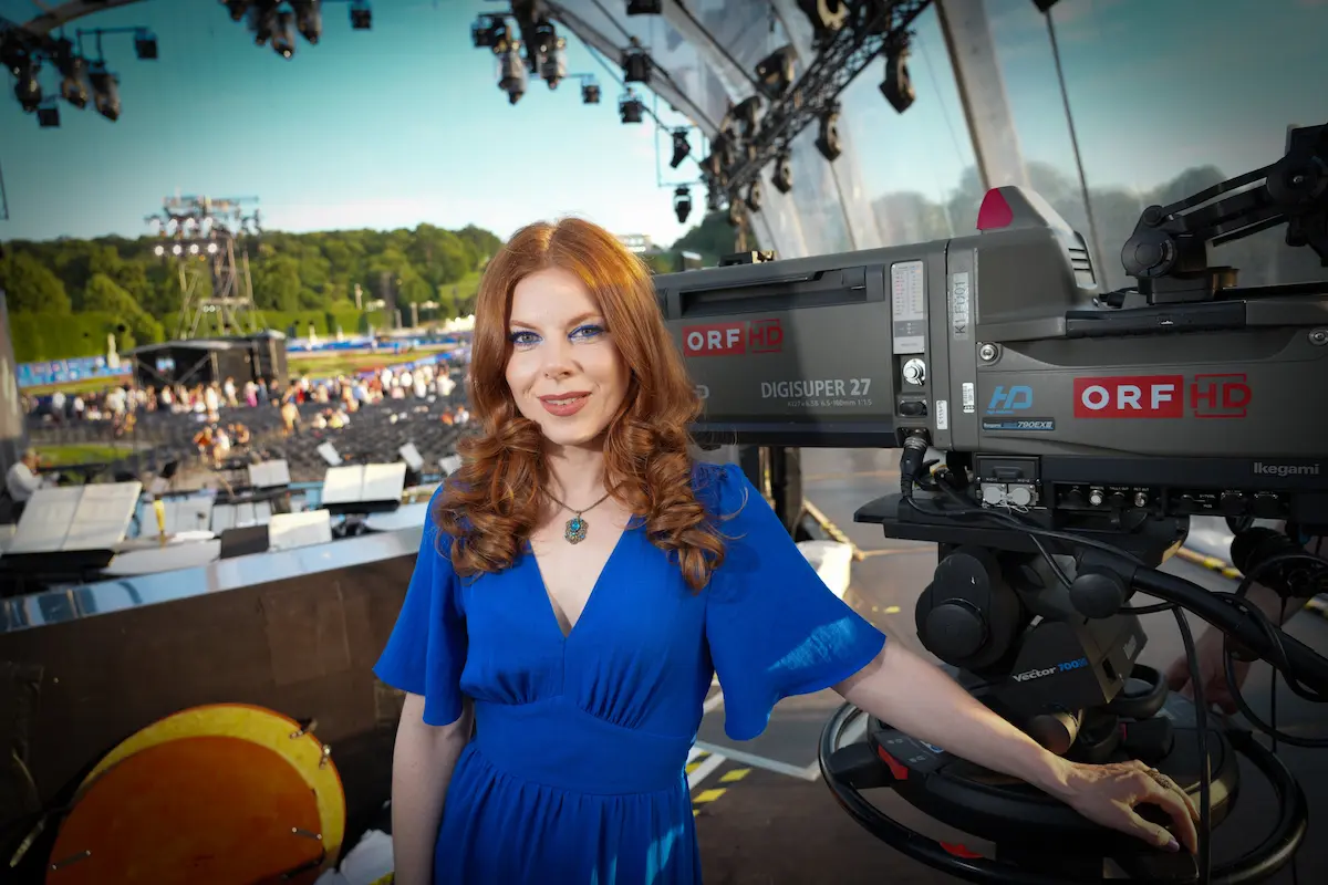 Teresa Vogl als Kommentatorin des Sommernachtskonzertes der Wiener Philharmoniker 2026 vor einer Fernsehkamera des ORF, im Hintergrund das Konzertgelände im Schlosspark Schönbrunn