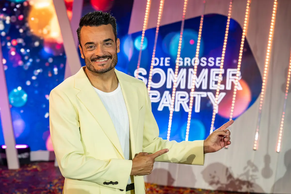 Giovanni Zarrella Show 29.8.2026 - Gäste und Informationen - hier im Bild der Moderator Giovanni Zarrella auf der Bühne in einem hellgelben Sommeranzug, im Hintergrund das Logo der Show